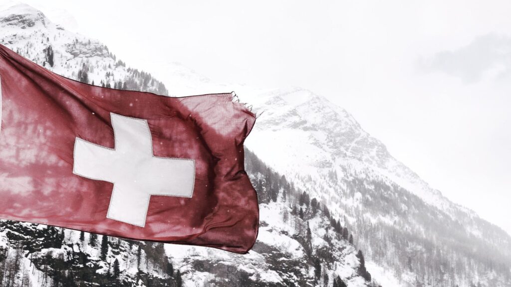 A swiss flag flying in front of a snowy mountain represents Switzerland's latest cybersecurity alert.